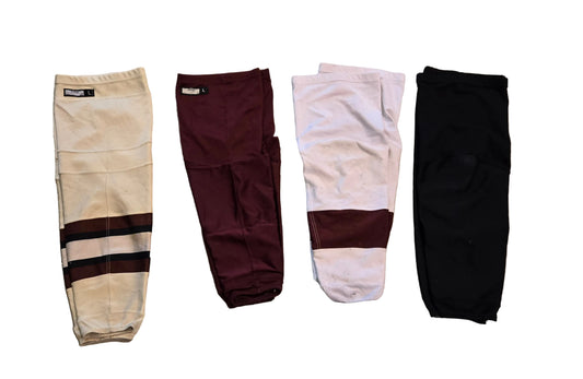 Four pairs of hockey socks, shown in cream, maroon, white and solid black.